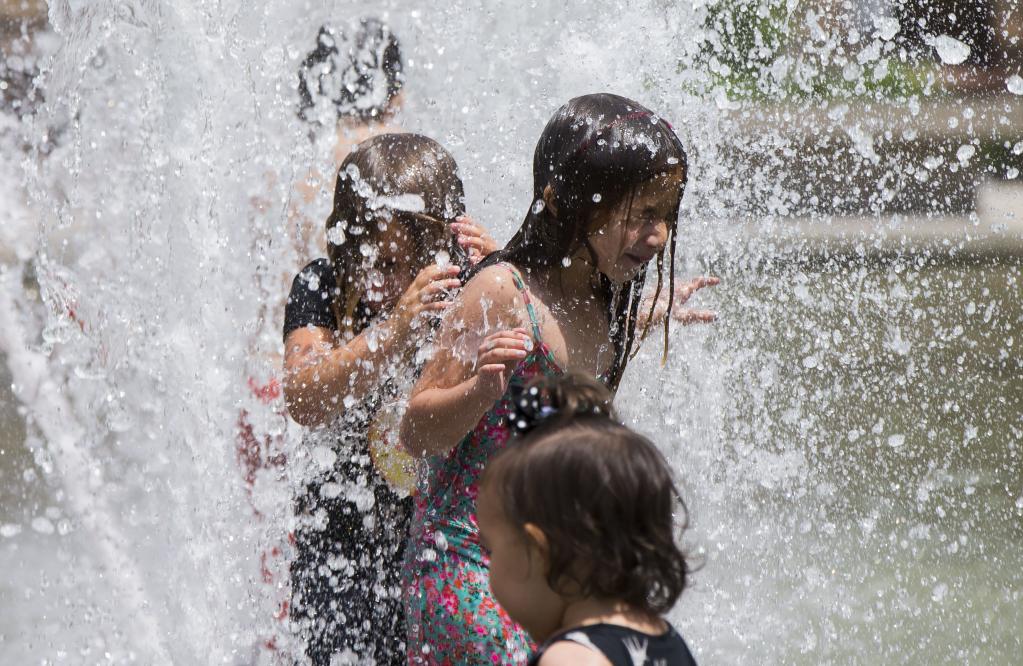 Niños se refrescan en una fuente en Toronto, Canadá