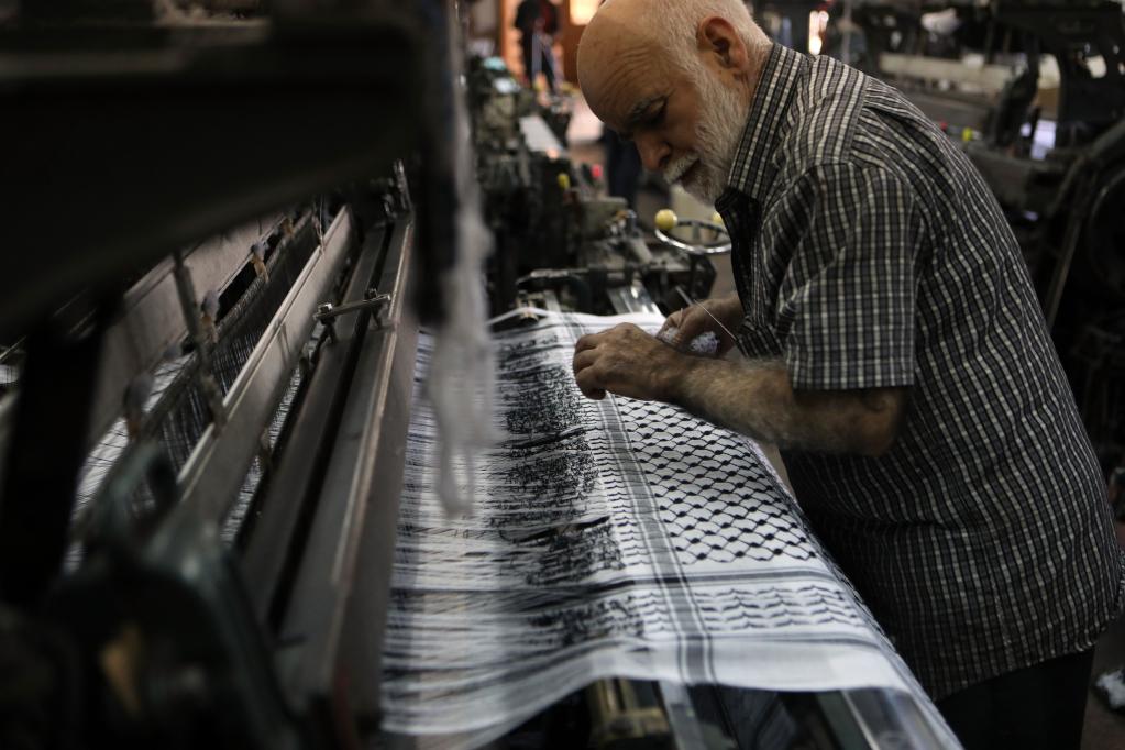 Trabajador labora en fábrica textil de kufiya en Hebrón
