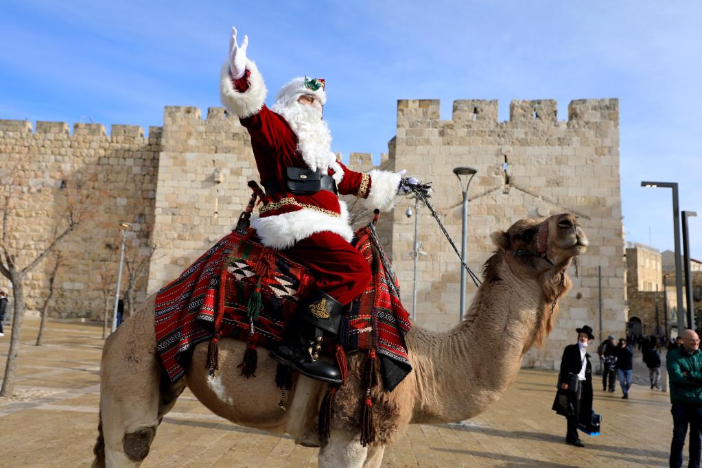 Hombre vestido como Santa Claus monta camello en la Ciudad Vieja de Jerusalén